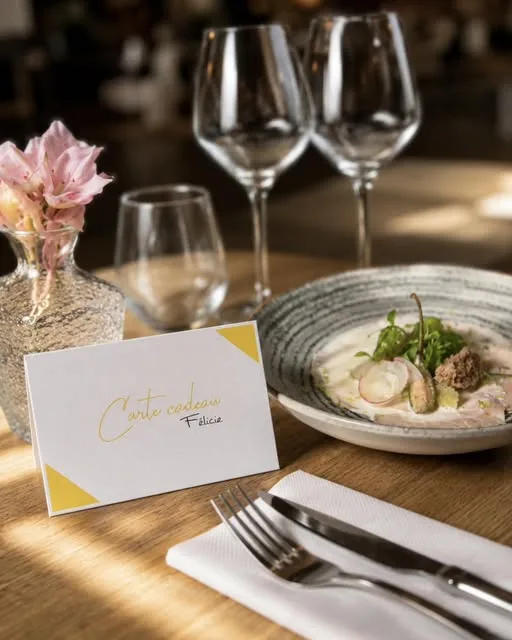 A Félicie gift card standing on a laid table, beside a plate